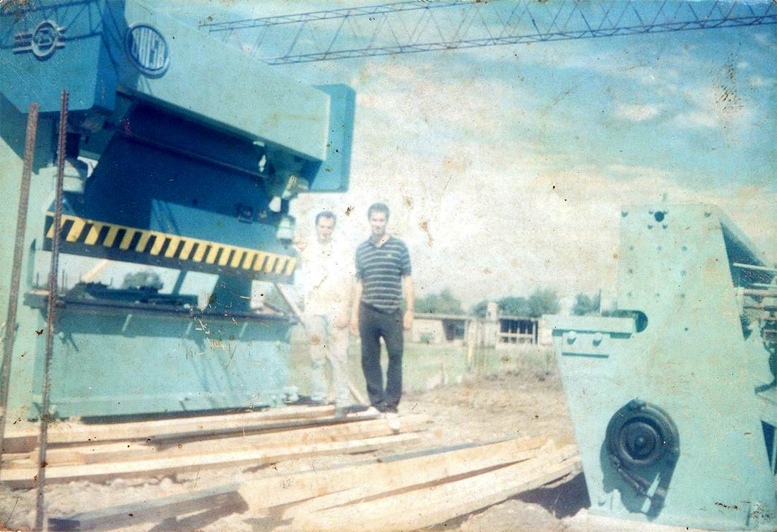 Dos personas junto a una guillotina y una plegadora al aire libre